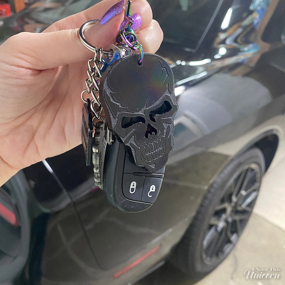 Black skull key chain, with car keys and black Dodge Challenger in the background