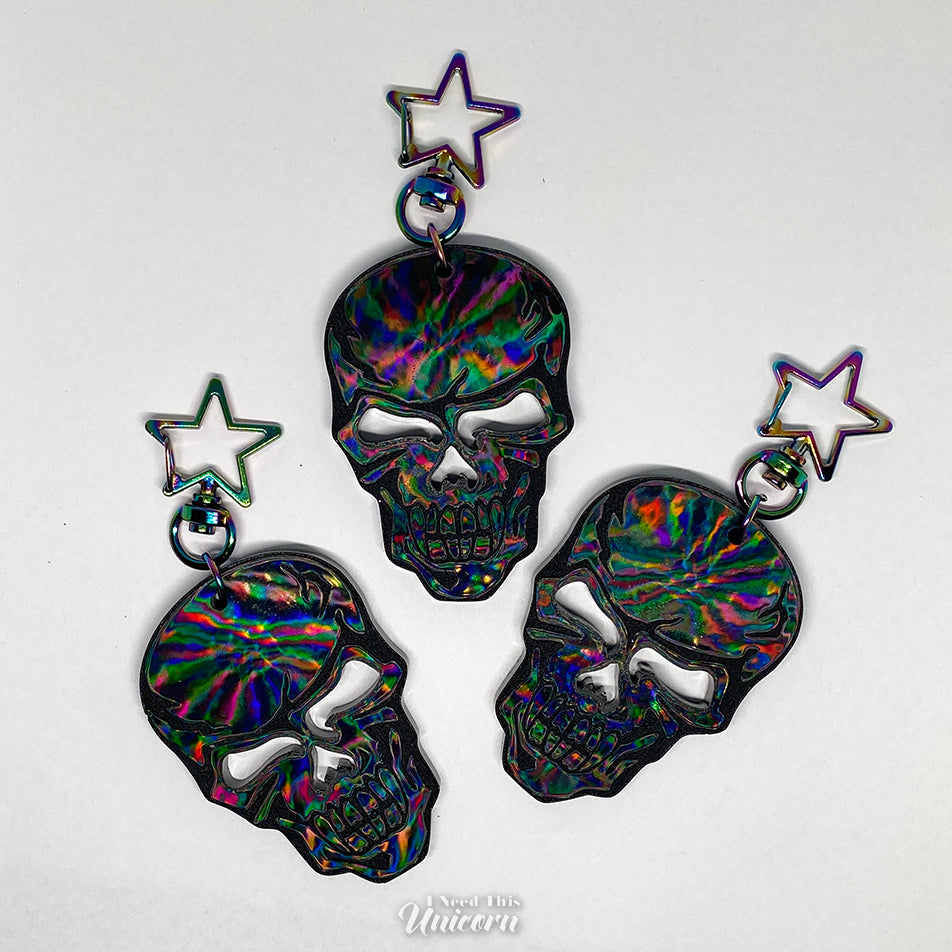 Black skull keychain with a holographic sheen and a rainbow oil-slick star clasp