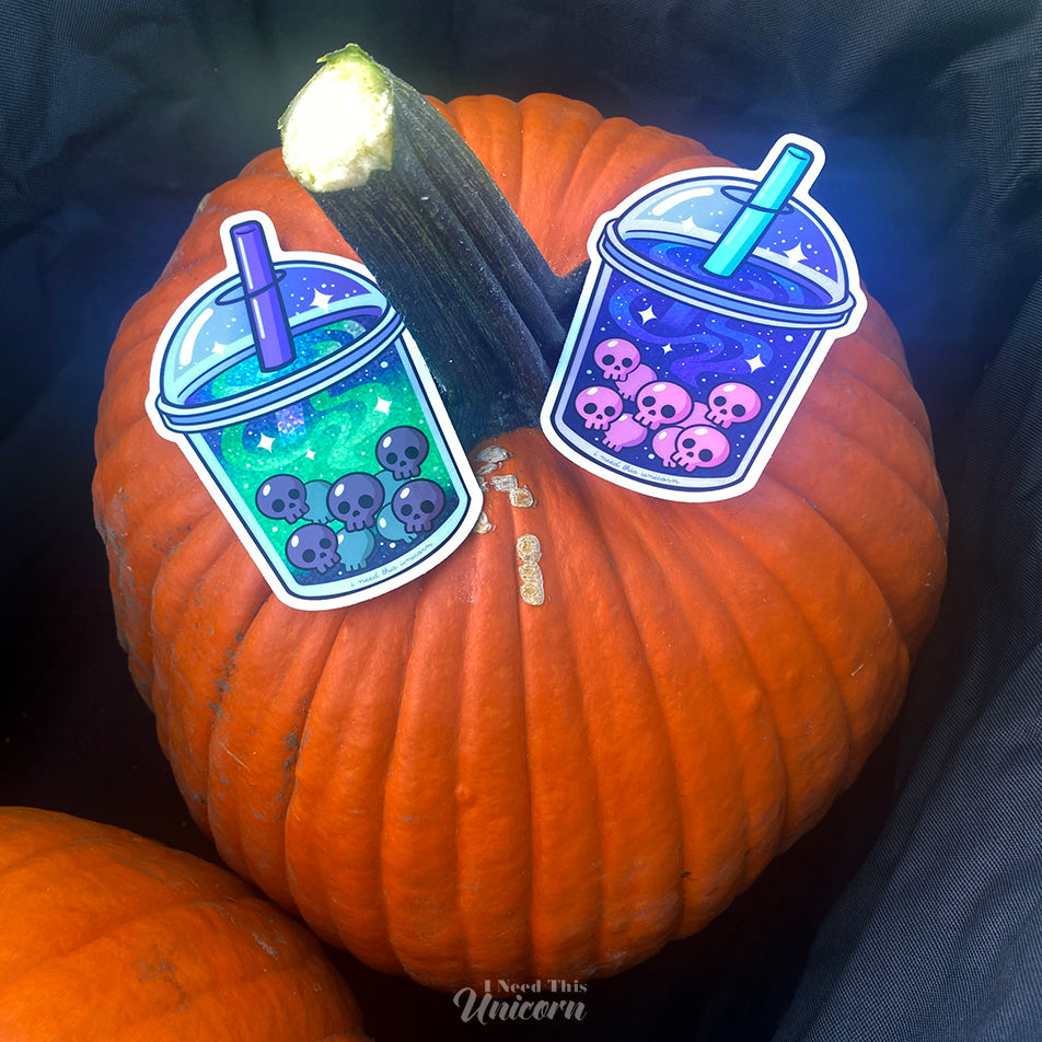 Pair of holographic boba stickers — Galactic Haunted Boba and Witch’s Brew Boba — featuring space and witchy drink designs with skull pearls on top of a Halloween pumpkin